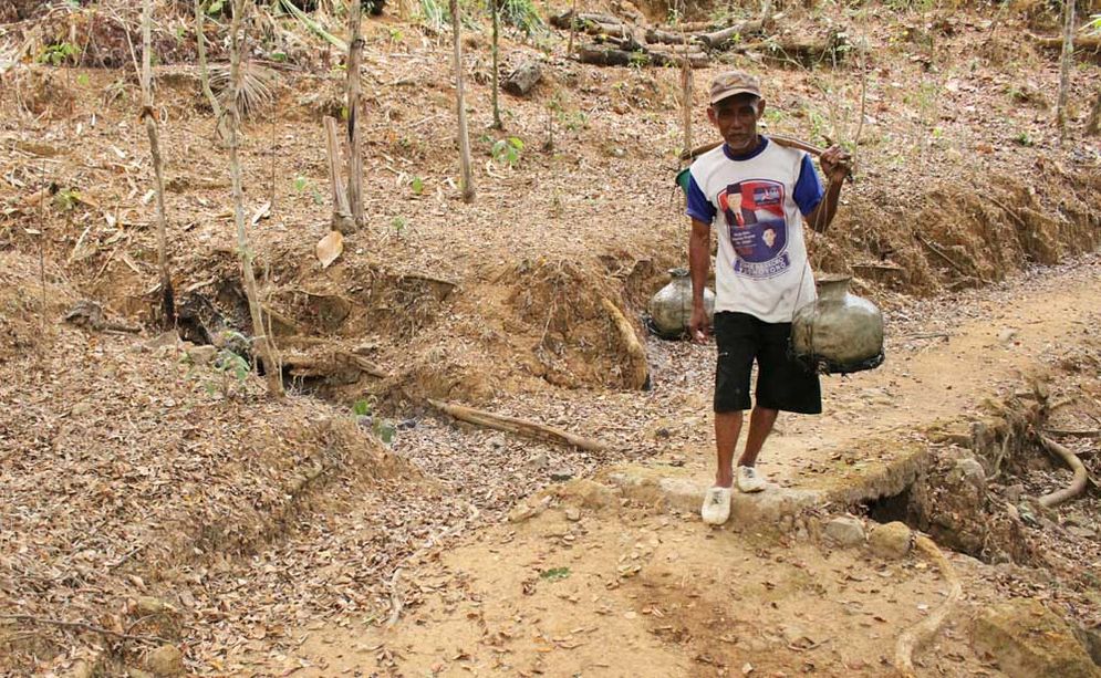 Seorang warga Dusun Pagergunung, Desa Sambong Kecamatan Pacitan memikul gentong berisi air untuk dibawa pulang kerumahnya sejauh 500 meter (19/10/2018)