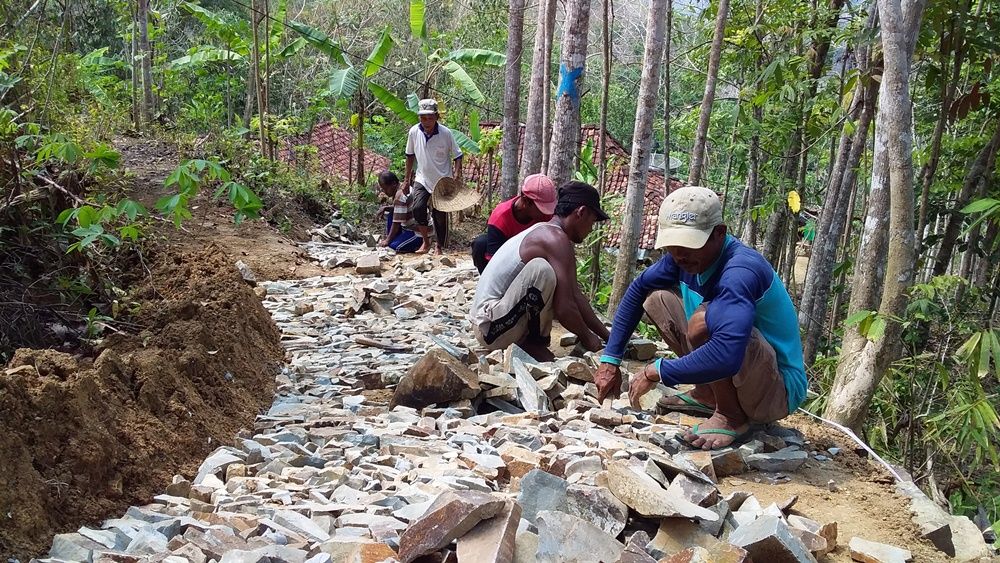 Warga sedang menata batu di jalan