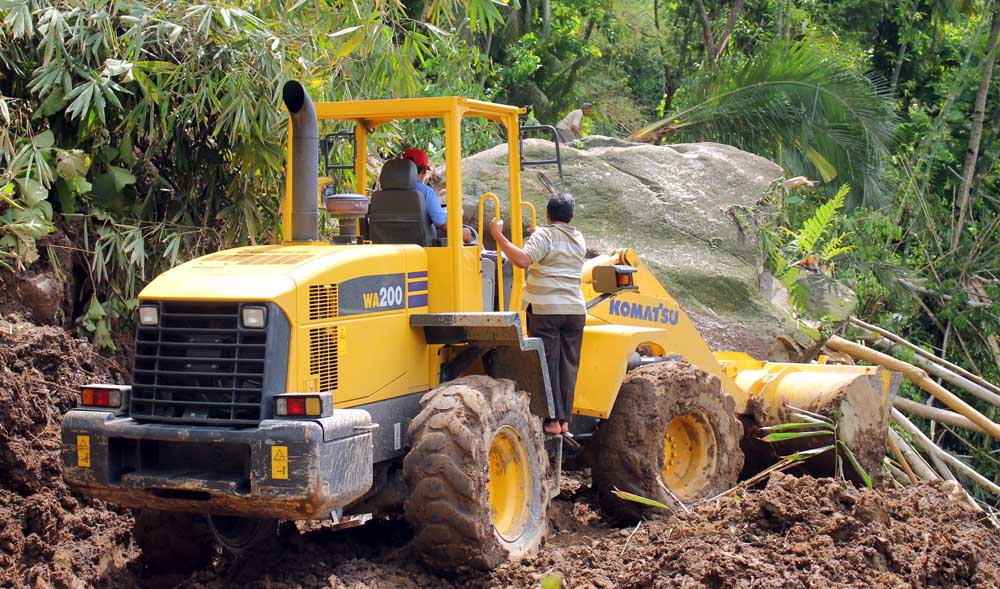 Wheel loader Dinas PUPR Kabupaten Pacitan mencoba menyingkirkan batu besar yang menutupi jalan