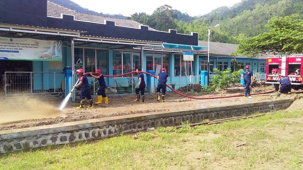 Petugas Damkar Pacitan bersihkan lumpur di depan Puskesmas Kebonagung