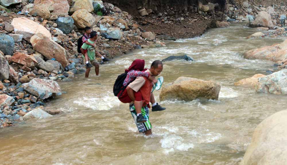 Sejumlah siswa SD digendong orang tuanya saat menyeberangi Sungai Grindulu saat hendak berangkat sekolah