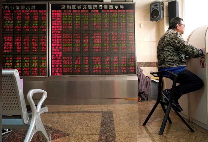 <p>Seorang investor duduk di sebelah papan harga di bursa saham Beijing/Reuters</p>
