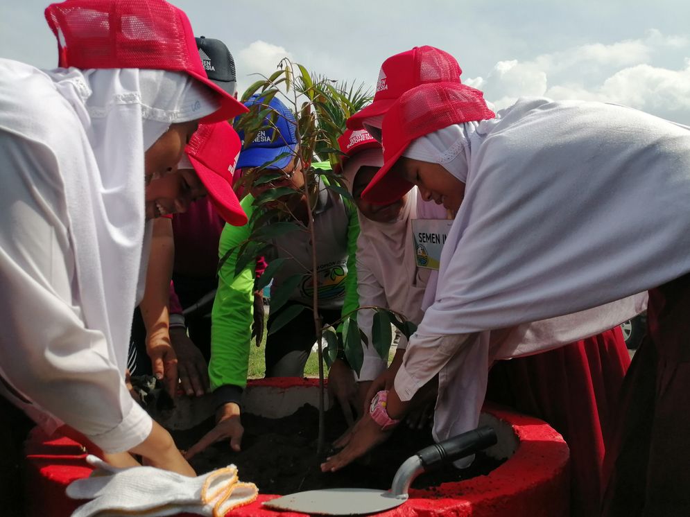 Para pelajar menanam pohon untuk melestarikan lingkungan di sekitar pabrik.