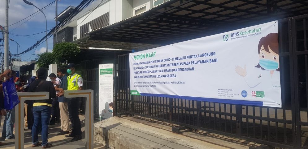 Screening suhu tubuh dan pemberian hand sanitizer sebelum masuk ke kantor pelayanan BPJS Kesehatan Cabang Surabaya.