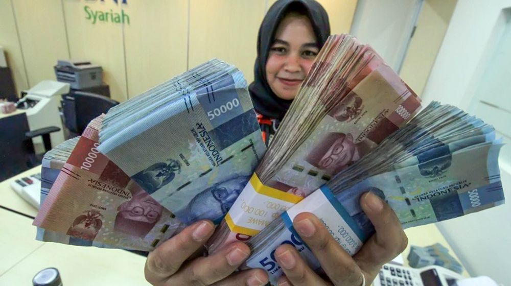 <p>Petugas bank menunjukkan uang saat melayani penarikan uang nasabah di bank BNI Syariah Lhokseumawe, Aceh, Jumat (13/3/2020).  Gubernur Bank Indonesia menyebutkan nilai tukar Rupiah terhadap Dolar Amerika Serikat kembali melemah di Rp14.640 per dolar AS atau sebesar 0,81% pada perdagangan pasar spot, Jumat (13/3) pagi, dampak sentimen kekhawatiran pelaku pasar keuangan terhadap virus Corona (COVID-19). ANTARA FOTO/Rahmad/ama.</p>
