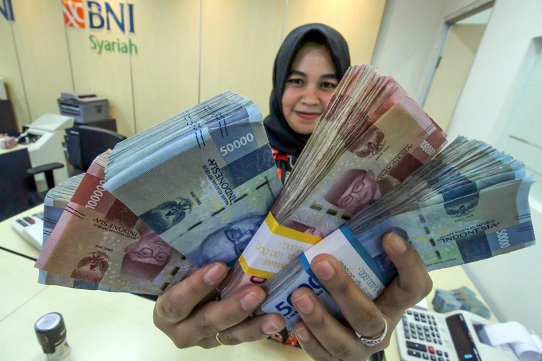 <p>Petugas bank menunjukkan uang saat melayani penarikan uang nasabah di bank BNI Syariah Lhokseumawe, Aceh, Jumat (13/3/2020).  Gubernur Bank Indonesia menyebutkan nilai tukar Rupiah terhadap Dolar Amerika Serikat kembali melemah di Rp14.640 per dolar AS atau sebesar 0,81% pada perdagangan pasar spot, Jumat (13/3) pagi, dampak sentimen kekhawatiran pelaku pasar keuangan terhadap virus Corona (COVID-19). ANTARA FOTO/Rahmad/ama.</p>
