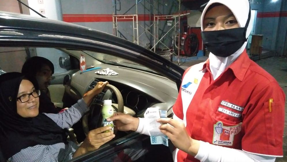 Petugas SPBU sedang melayani konsumen dengan memberikan susu segar untuk menjaga kondisi tubuh tetap segar di saat pandemi corona.