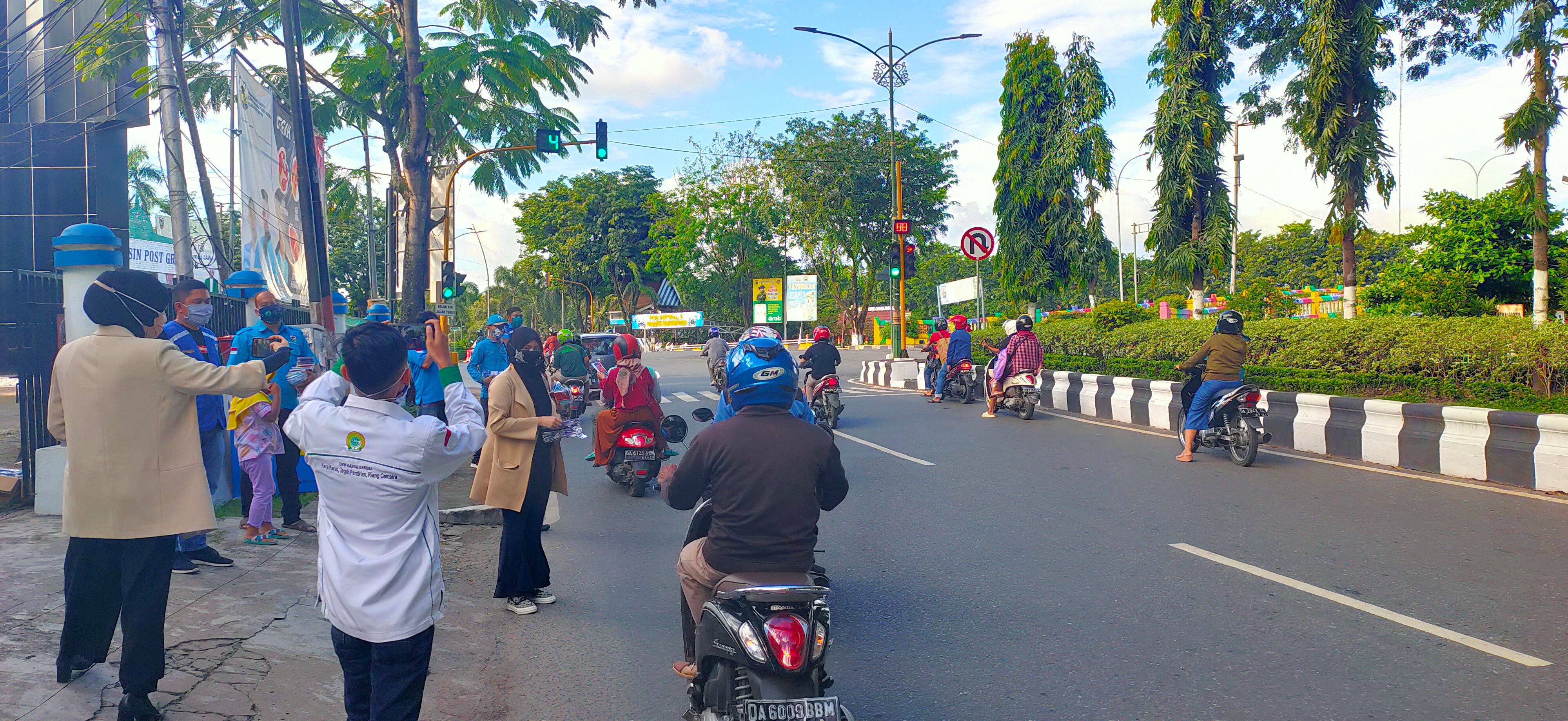 Anggota dan pengurus KNPI Kalsel membagikan masker kepada pengendara yang melintas