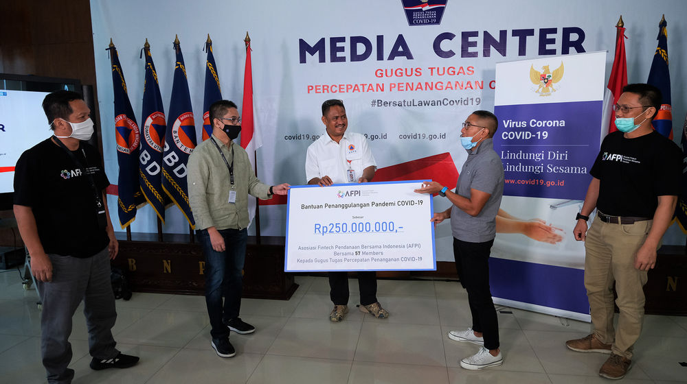 <p>Ketua Umum Asosiasi Fintech Pendanaan Bersama Indonesia (AFPI), Adrian Gunadi (kedua kanan) menyerahkan bantuan dana senilai Rp 250 juta rupiah kepada Koordinator Relawan Gugus Tugas Percepatan Penanganan Covid-19, Andre Rahadian (kedua kiri) disaksikan Tenaga Ahli BNPB Bidang Media, Egy Massadiah (tengah), Ketua Harian AFPI, Kuseryansyah (Kiri) dan Kepala Bidang Humas dan Kelembagaan AFPI, Tumbur Pardede (kanan) di Media Center Gugus Tugas Percepatan Penanganan Covid-19, Kantor Badan Nasional Penanggulangan Bencana (BNPB), Jakarta, Kamis (9/4/2010). Foto: Ismail Pohan/TrenAsia</p>