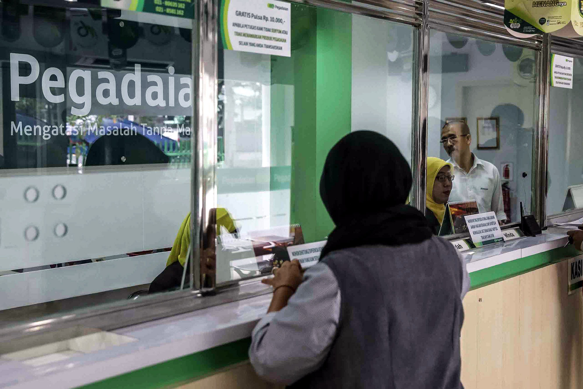 <p>Petugas melayani warga saat melakukan transaksi di gerai pegadaian Jakarta. Foto: Ismail Pohan/TrenAsia</p>

