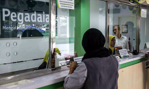 <p>Petugas melayani warga saat melakukan transaksi di gerai pegadaian Jakarta. Foto: Ismail Pohan/TrenAsia</p>
