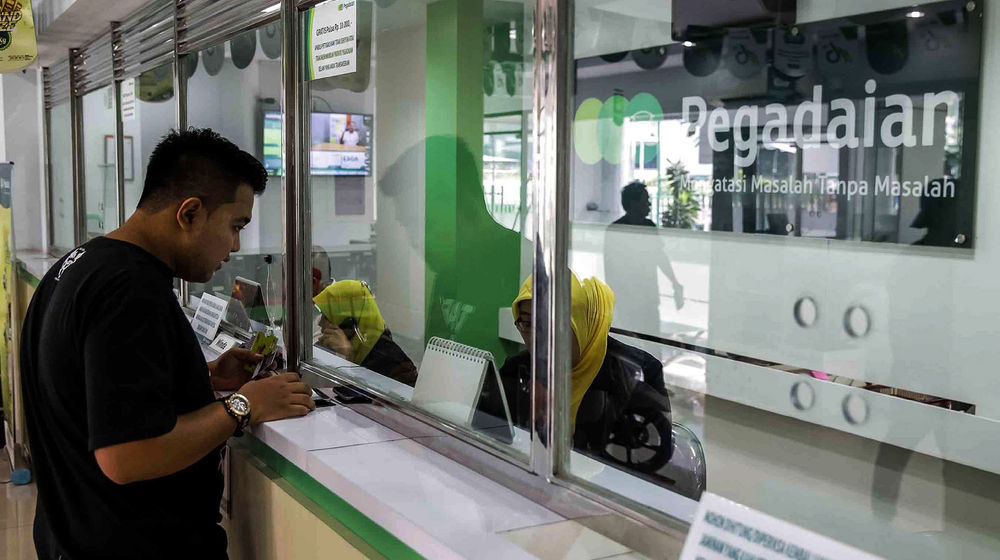 <p>Petugas melayani warga saat melakukan transaksi di gerai pegadaian Jakarta. Foto: Ismail Pohan/TrenAsia</p>
