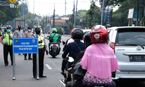 <p>Petugas Polantas bersama Dinas Perhubungan (Dishub) melaksanakan pengawasan dalam penerapan Pembatasan Sosial Berskala Besar (PSBB) di Jalan Raya Bogor perbatasan Depok-Jakarta, Jumat (10/4/2020). Petugas memberhentikan kendaraan untuk mengimbau kewajiban memakai masker dan aturan penumpang dalam satu kendaraan. Polisi pun mengingatkan warga jika tidak ada keperluan penting atau mendesak agar kembali ke rumah. Foto: Ismail Pohan/TrenAsia</p>
