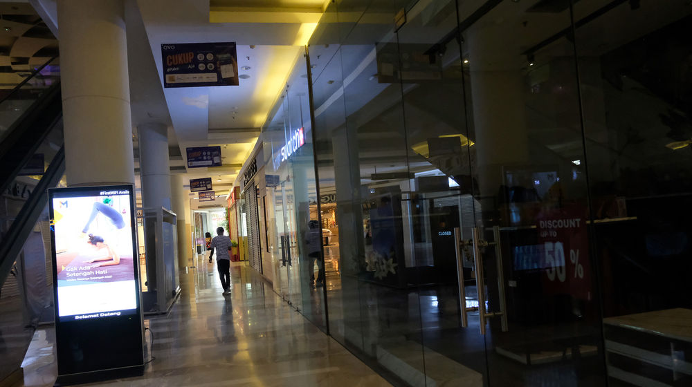 <p>Warga melintas di antara tenant yang tutup di area salah satu pusat perbelanjaan di kawasan Pejaten, Jakarta, Jum’at (10/4/2020). Penerapan Pembatasan Sosial Berskala Besar membuat sejumlah pusat perbelanjaan kembali memperpanjang masa penutupan sampai 19 April sebagai upaya mencegah penyebaran wabah COVID-19. Foto: Ismail Pohan/TrenAsia</p>
