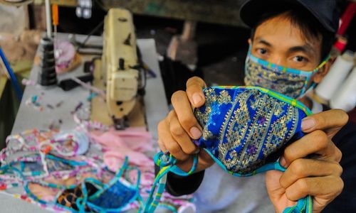 <p>Pekerja menunjukkan masker kain produksi penjahit konveksi di Kampung Cibangkur, Lebak, Banten, Senin (6/4/2020). Tingginya permintaan masker membuat penjahit konveksi di daerah tersebut dapat memproduksi 500-1000 lembar masker kain per hari dengan harga Rp5.000 per lembarnya, dan dipasarkan ke sejumlah kota seperti Serang, Cilegon, Tangerang, dan Jakarta. ANTARA FOTO/Muhammad Bagus Khoirunas/hp.</p>
