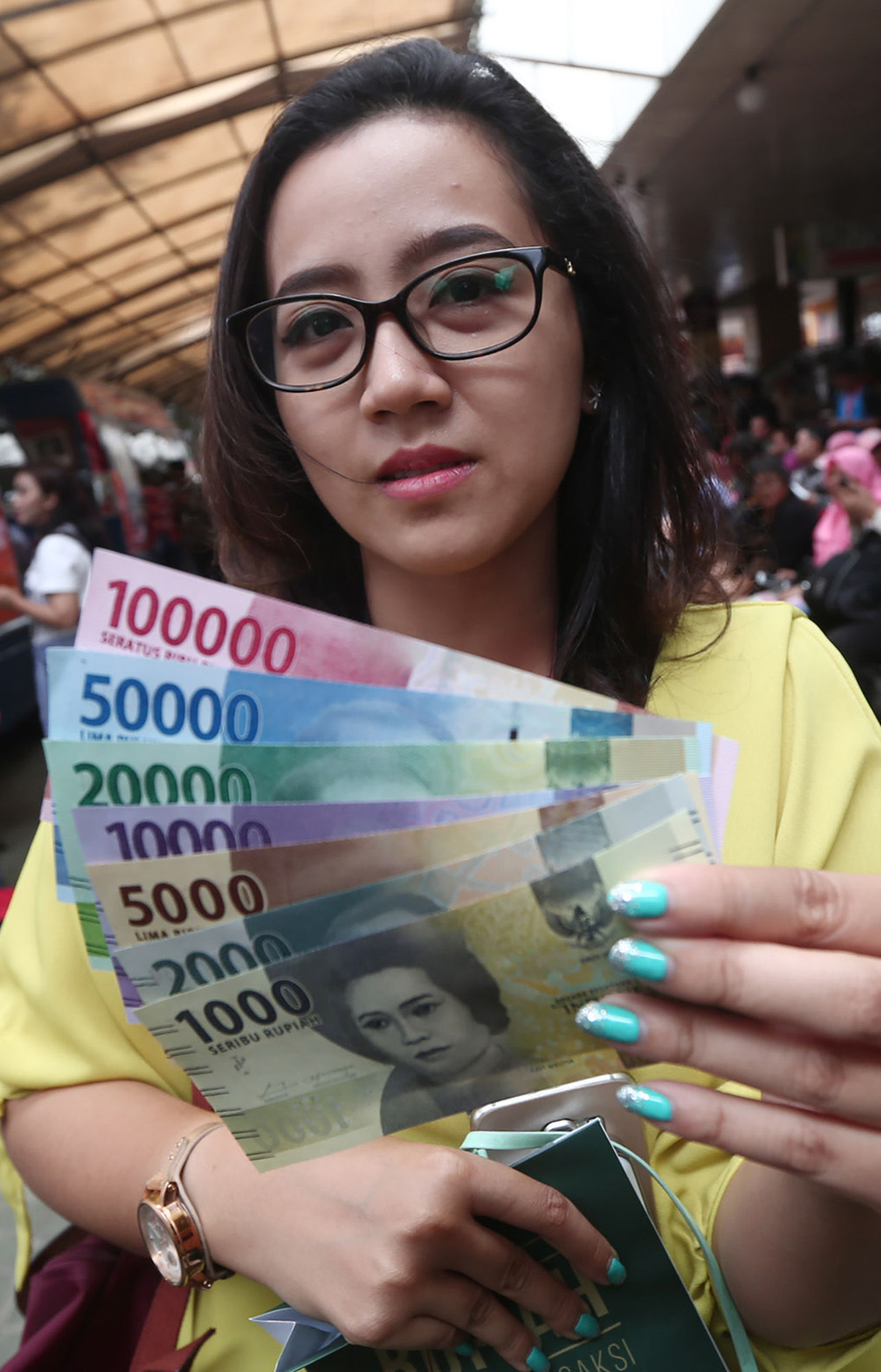 <p>Warga menunjukkan uang kertas rupiah baru tahun emisi 2016 usai melakukan penukaran di pusat perbelanjaan di Jakarta, Senin (19/12). Foto: Ismail Pohan/TrenAsia</p>
