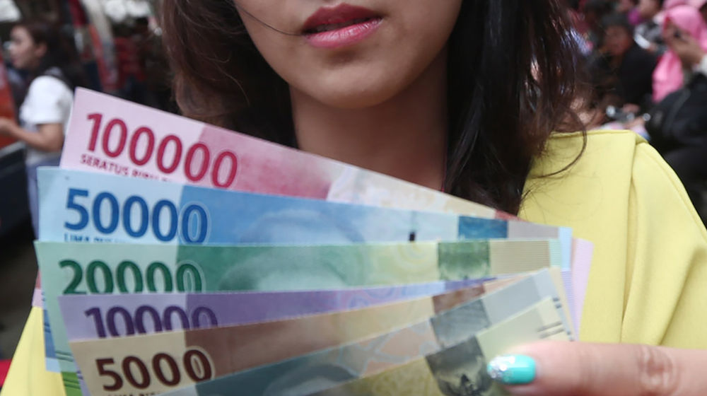 <p>Warga menunjukkan uang kertas rupiah baru tahun emisi 2016 usai melakukan penukaran di pusat perbelanjaan di Jakarta, Senin (19/12). Foto: Ismail Pohan/TrenAsia</p>
