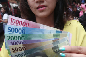 <p>Warga menunjukkan uang kertas rupiah baru tahun emisi 2016 usai melakukan penukaran di pusat perbelanjaan di Jakarta, Senin (19/12). Foto: Ismail Pohan/TrenAsia</p>
