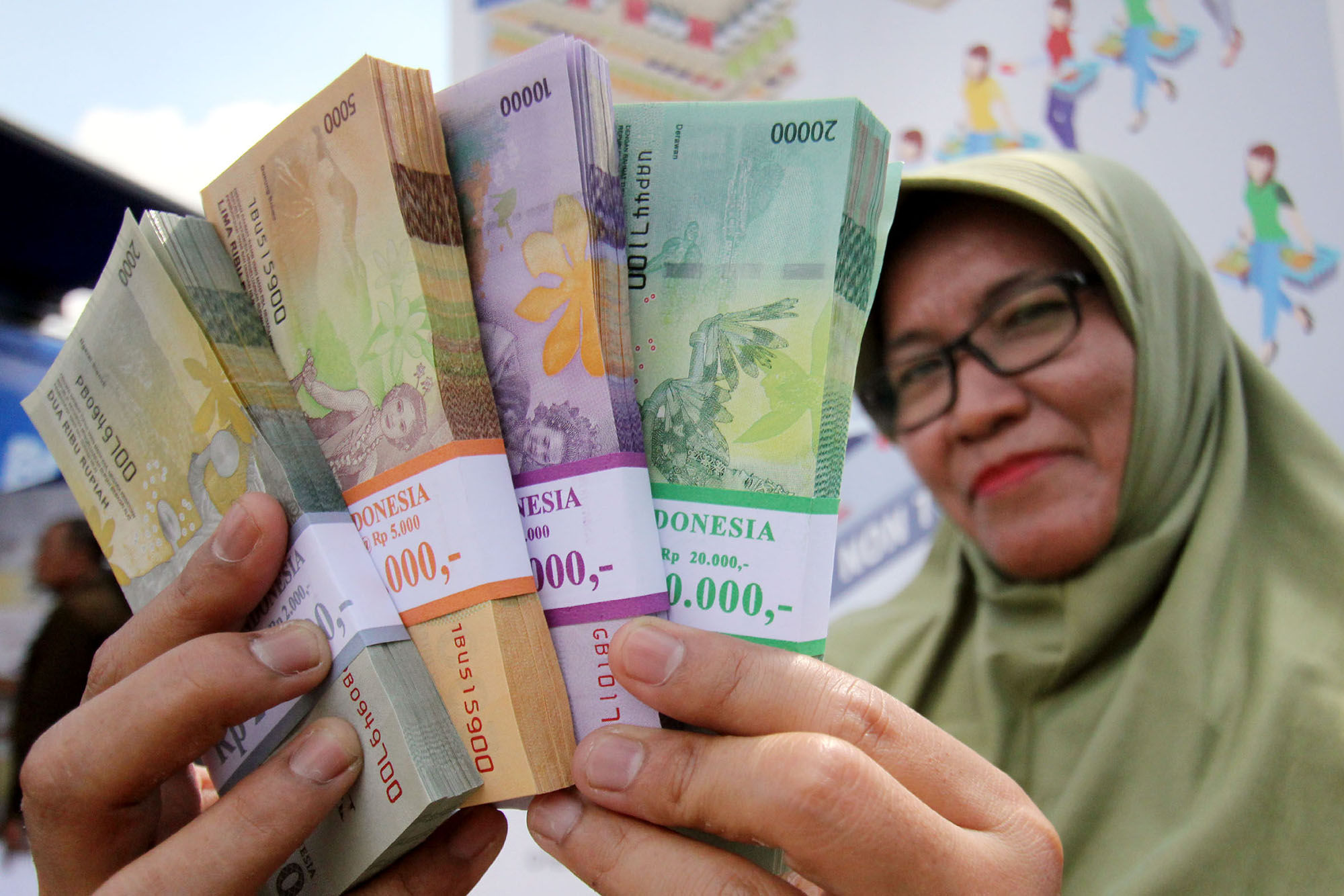 <p>Warga menunjukan uang pecahan yang telah di tukarkan di Lapangan IRTI Monas, Jakarta. Foto: Ismail Pohan/TrenAsia</p>

