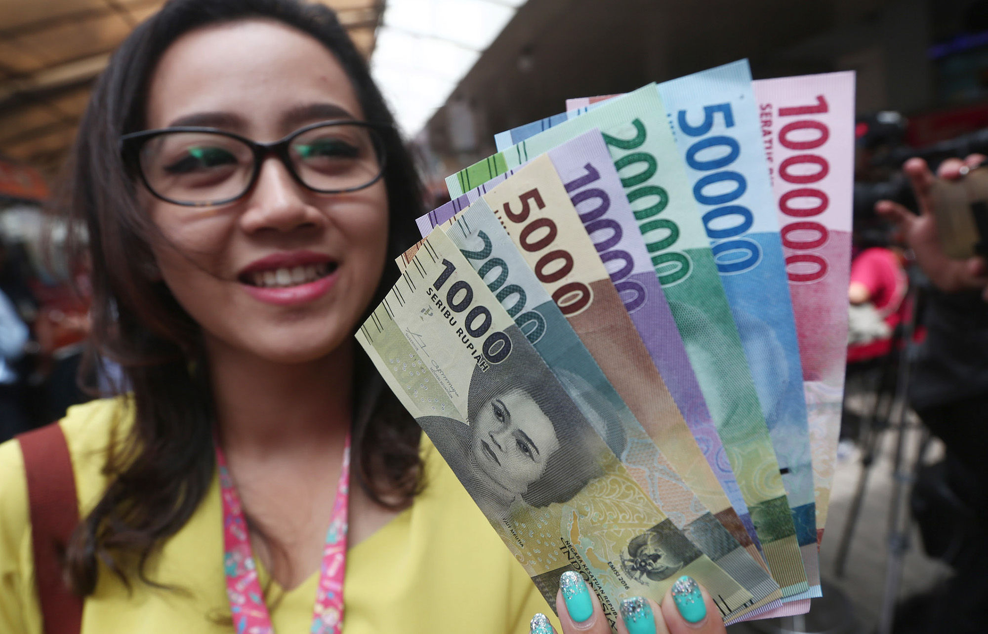 <p>Warga menunjukkan uang kertas rupiah baru tahun emisi 2016 usai melakukan penukaran di pusat perbelanjaan di Jakarta, Senin (19/12). Foto: Ismail Pohan/TrenAsia</p>
