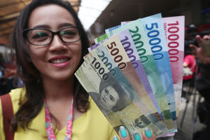 <p>Warga menunjukkan uang kertas rupiah baru tahun emisi 2016 usai melakukan penukaran di pusat perbelanjaan di Jakarta, Senin (19/12). Foto: Ismail Pohan/TrenAsia</p>
