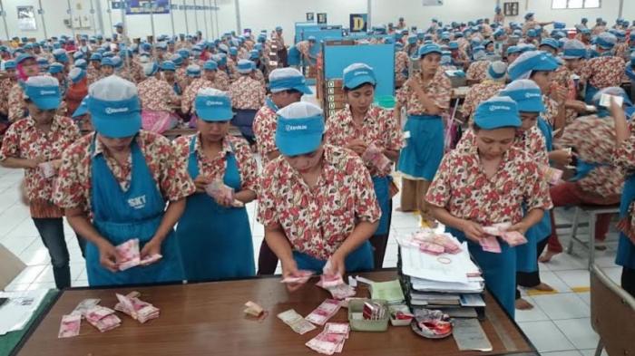 Karyawan PT Djarum Kudus menghitung uang THR yang diterimanya.
