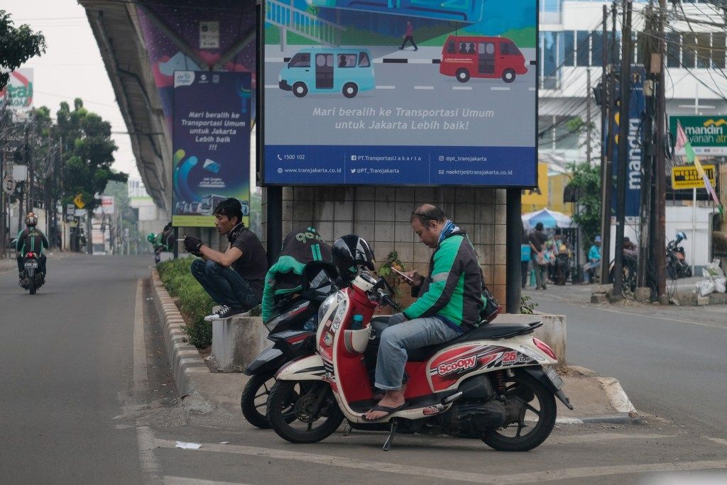 <p>Sejumlah Driver Ojek Online menunggu orderan di Jakarta, Jumat (10/4/2020). Peraturan Gubernur DKI Jakarta dalam pelaksanaan PSBB mengatur angkutan roda dua seperti ojek online maupun ojek konvensional dilarang membawa penumpang. Foto: Ismail Pohan/TrenAsia</p>
