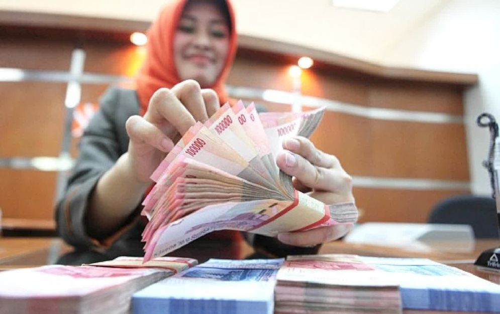 Seorang petugas bank tengah menghitung uang kertas rupiah.Foto: ist