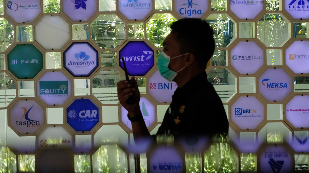 <p>Petugas keamanan berjaga dengan latar belakang logo beberapa perusahaan asuransi di Kantor Asosiasi Asuransi Jiwa Indonesia (AAJI) di Jakarta, Rabu 10 Juni 2020. Berdasarkan data Otoritas Jasa Keuangan (OJK) pada Maret 2020 nilai aset asuransi jiwa mengalami penurunan secara tahun berjalan maupun secara tahunan sedangkan asuransi umum justru tumbuh, industri asuransi jiwa mencatatkan total aset Rp 529,2 trilun atau menurun 10,4 % (ytd) dari Desember 2019 senilai Rp 590,7 triliun. Foto: Ismail Pohan/TrenAsia</p>
