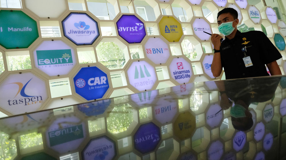 <p>Petugas keamanan berjaga dengan latar belakang logo beberapa perusahaan asuransi di Kantor Asosiasi Asuransi Jiwa Indonesia (AAJI) di Jakarta, Rabu 10 Juni 2020. Foto: Ismail Pohan/TrenAsia</p>
