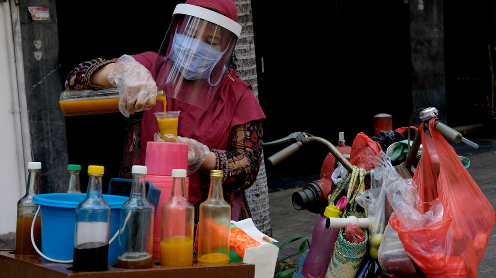 <p>Tidar (46), membuatkan jamu untuk pelanggannya di Pasar Baru, Jakarta Pusat, Kamis 11 Juni 2020. Penjual jamu tradisional keliling ini tampak mematuhi protokol kesehatan pencegahan COVID-19 dengan mengenakan masker, face shield, dan sarung tangan dalam melayani pelanggan setianya di masa PSBB transisi.  Foto: Ismail Pohan/TrenAsia</p>
