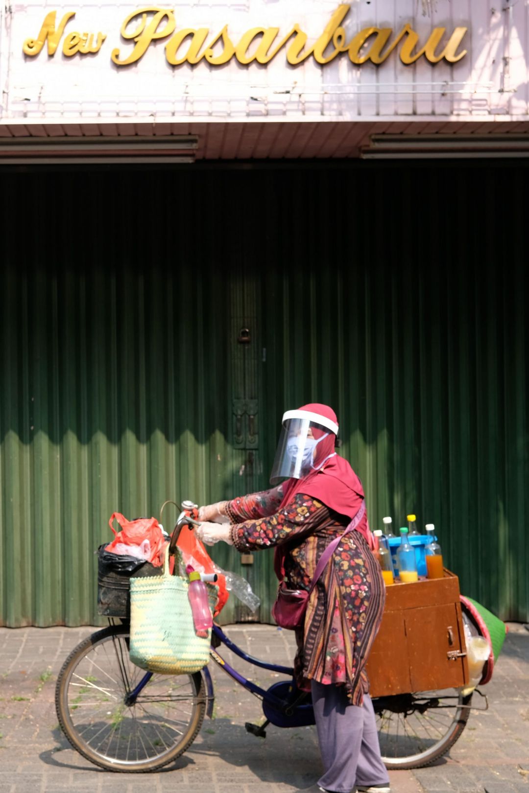 <p>Tidar (46), berpose dengan sepedanya saat berjualan jamu keliling di Pasar Baru, Jakarta Pusat, Kamis 11 Juni 2020. Penjual jamu tradisional keliling ini tampak mematuhi protokol kesehatan pencegahan COVID-19 dengan mengenakan masker, face shield, dan sarung tangan dalam melayani pelanggan setianya di masa PSBB transisi.  Foto: Ismail Pohan/TrenAsia</p>
