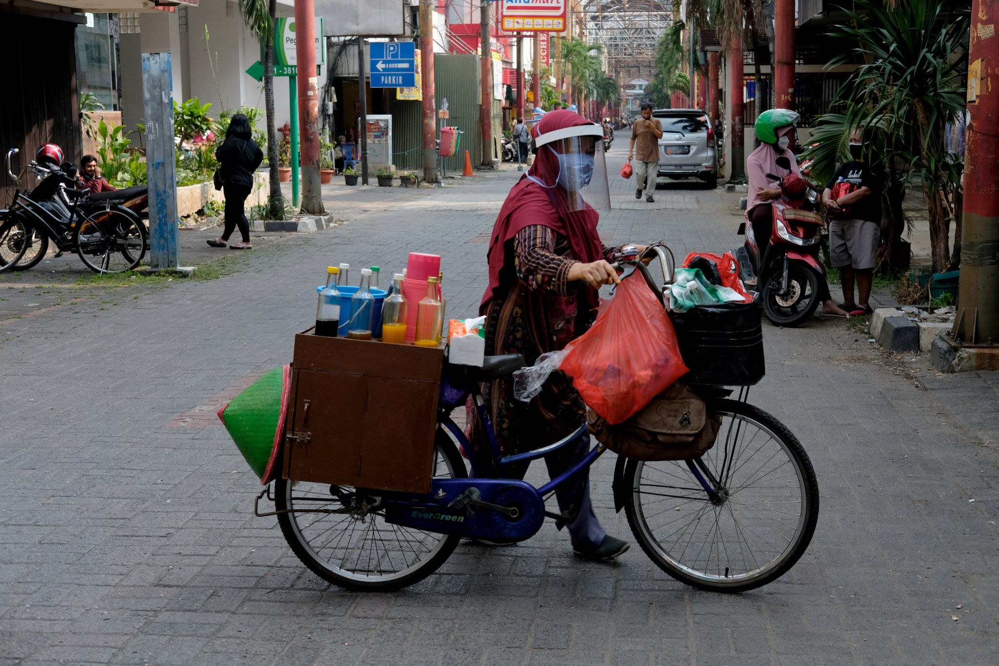 <p>Tidar (46), mendorong sepeda nya berjualan jamu keliling di Pasar Baru, Jakarta Pusat, Kamis 11 Juni 2020. Penjual jamu tradisional keliling ini tampak mematuhi protokol kesehatan pencegahan COVID-19 dengan mengenakan masker, face shield, dan sarung tangan dalam melayani pelanggan setianya di masa PSBB transisi. Foto: Ismail Pohan/TrenAsia</p>
