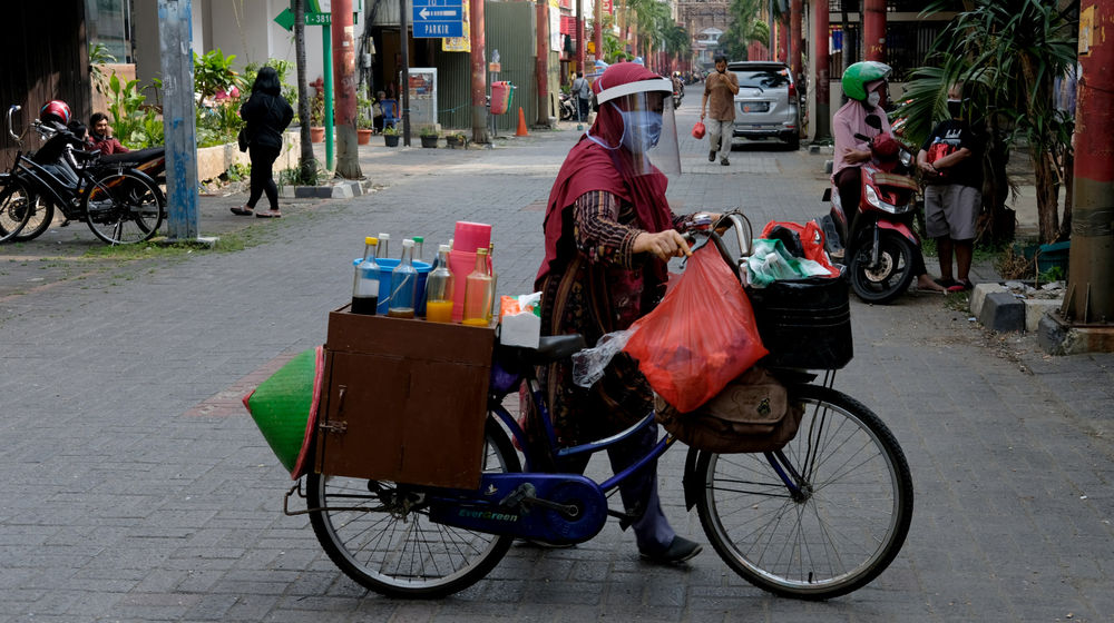<p>Tidar (46), mendorong sepeda nya berjualan jamu keliling di Pasar Baru, Jakarta Pusat, Kamis 11 Juni 2020. Penjual jamu tradisional keliling ini tampak mematuhi protokol kesehatan pencegahan COVID-19 dengan mengenakan masker, face shield, dan sarung tangan dalam melayani pelanggan setianya di masa PSBB transisi. Foto: Ismail Pohan/TrenAsia</p>
