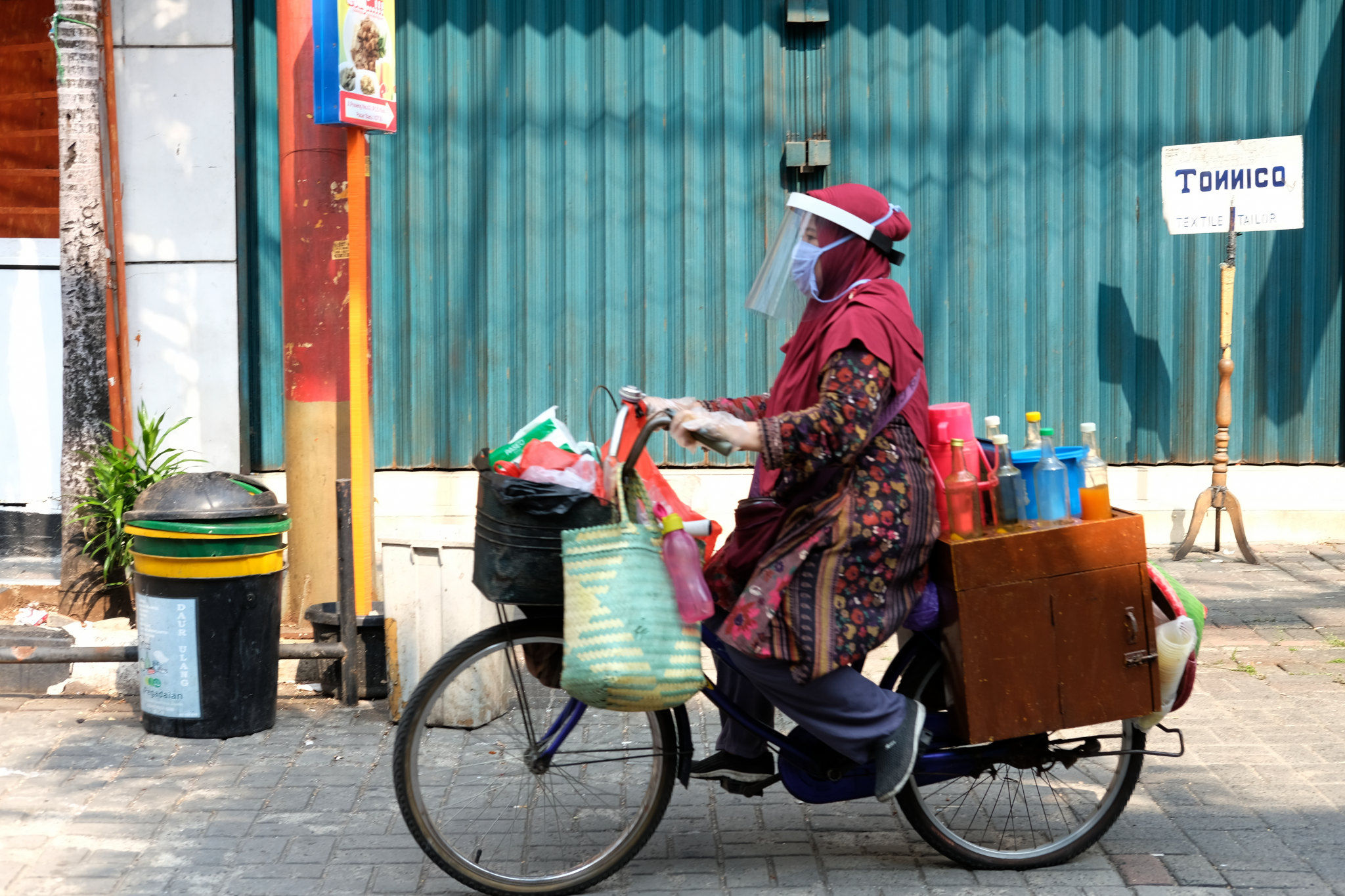 <p>Tidar (46), mengayuh sepeda nya berjualan jamu keliling di Pasar Baru, Jakarta Pusat, Kamis 11 Juni 2020. Penjual jamu tradisional keliling ini tampak mematuhi protokol kesehatan pencegahan COVID-19 dengan mengenakan masker, face shield, dan sarung tangan dalam melayani pelanggan setianya di masa PSBB transisi.  Foto: Ismail Pohan/TrenAsia</p>

