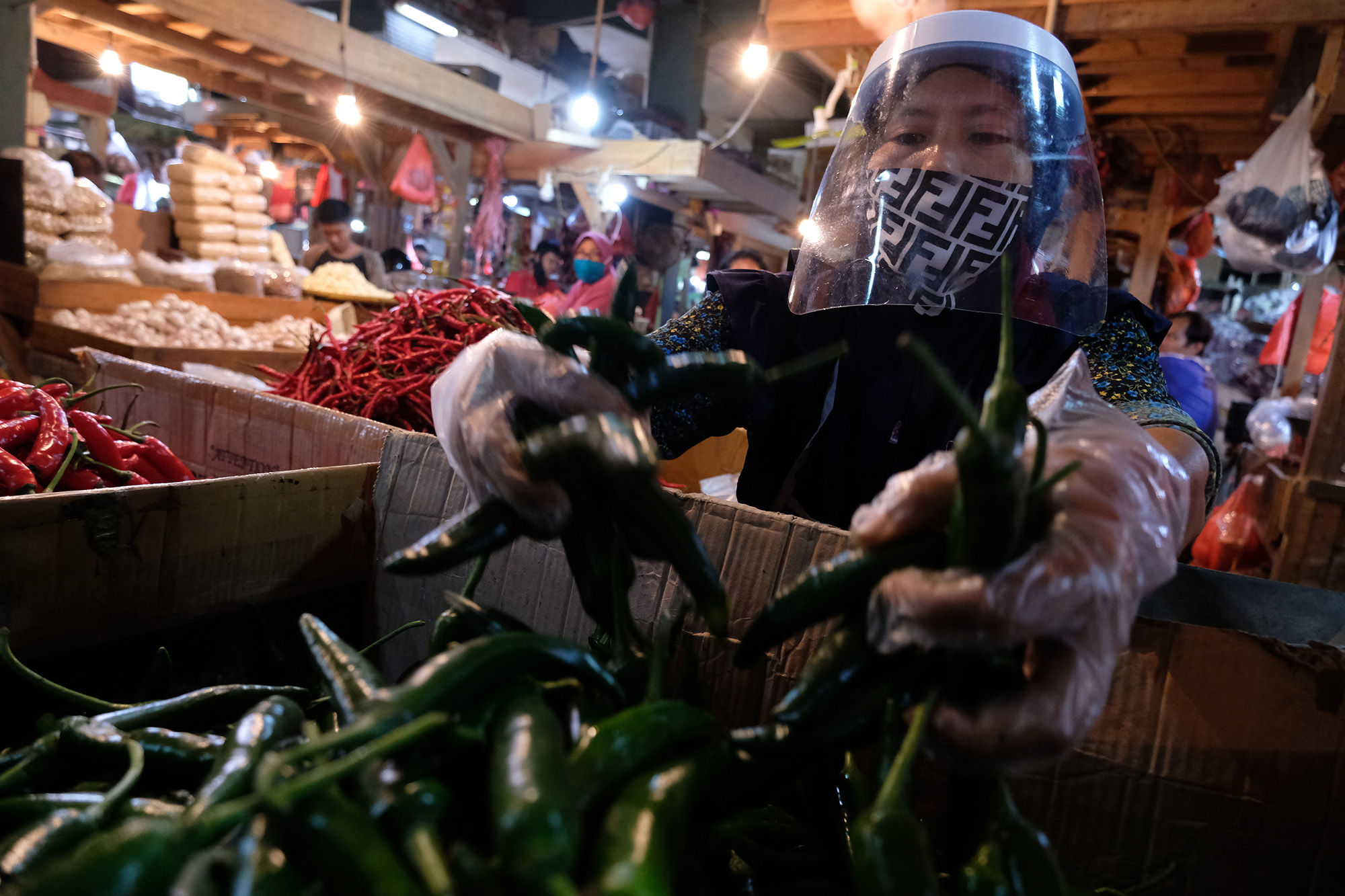 <p>Pedagang mengenakan face shield dan sarung tangan menata barang dagangannya di los sayuran Pasar Senen, Jakarta, 1 Juni 2020. Kementerian Perdagangan menyiapkan pedoman bagi penyelenggara kegiatan perdagangan untuk diterapkan pada saat kenormalan baru (new normal). Saat era new normal, para pedagang di pasar rakyat diwajibkan menggunakan masker, face shield, dan sarung tangan selama beraktivitas. Selain itu, kegiatan pasar juga hanya diperbolehkan pada pukul 06.00 hingga 11.00. Para pedagang yang diperbolehkan berjualan adalah mereka yang memiliki suhu tubuh di bawah 37,3 derajat celcius. Foto: Ismail Pohan/TrenAsia</p>
