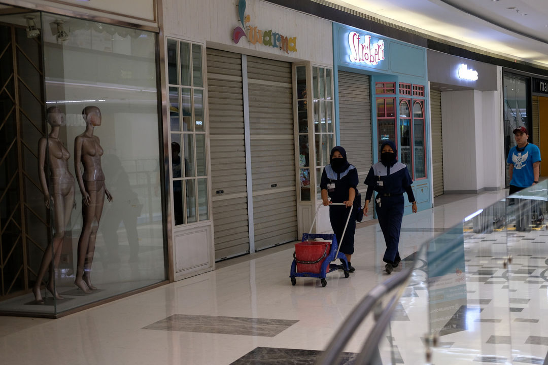 <p>Pekerja melintas di depan tenant yang masih tutup di area Lippo Mall Puri, Jakarta Barat, Rabu 3 Juni 2020. Lippo Mall Indonesia menyiapkan prosedur menuju new normal di  seluruh mall menyambut pembukaan kembali. Prosedur kebersihan dan keamanan pengunjung dan karyawan yang telah disiapkan mengacu pada protokol kesehatan guna mendukung Pemerintah dalam menerapkan new normal agar masyarakat tetap produktif, disiplin, serta waspada terhadap penyebaran Covid-19. Foto: Ismail Pohan/TrenAsia</p>
