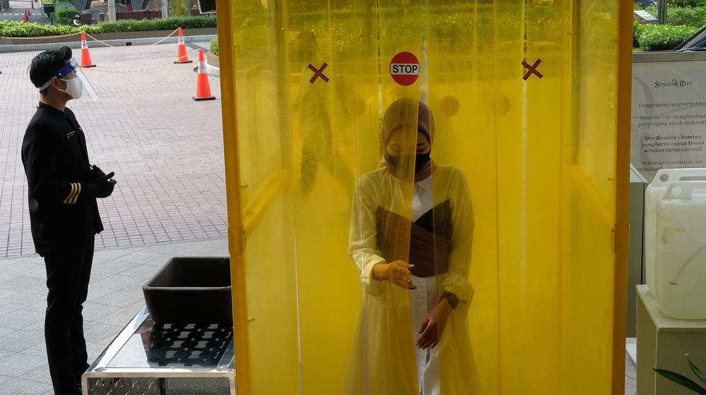 <p>Pengunjung melewati bilik penyemprotan disinfektan saat akan memasuki mall Senayan City, Jakarta, Selasa 9 Juni 2020. Senayan City siap menyambut pengunjung kembali pada Senin, 15 Juni 2020 dengan menerapkan berbagai protokol pencegahan COVID-19 seperti penggunaan wajib masker, pengecekan suhu tubuh, penggunaan hand sanitizer, UV-C sterilizer untuk kantong belanja hingga tombol lift yang dapat beroperasi tanpa disentuh untuk kenyamanan pengunjung selama masa transisi dan seterusnya. Foto: Ismail Pohan/TrenAsia</p>
