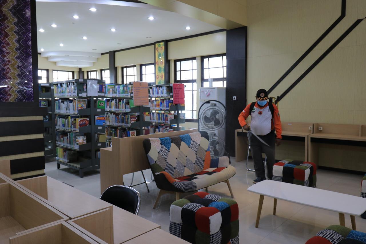 Petugas sedang menyemprotkan cairan disfektan di kawasan perpustakaan