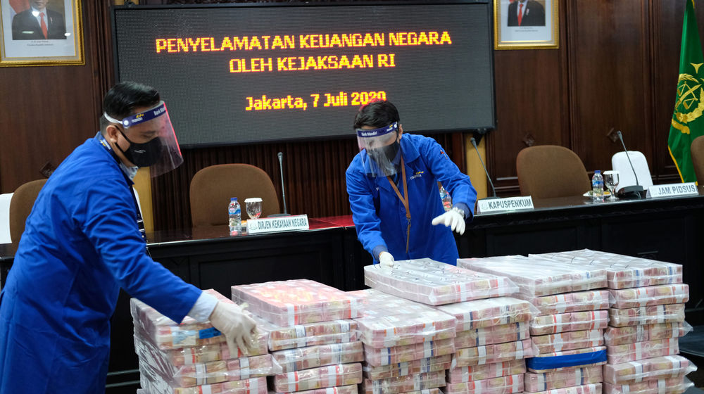 <p>Petugas merapikan barang bukti berupa uang sitaan di kantor Kejagung, Jakarta, Selasa, 7 Juli 2020. Kejagung mengeksekusi kilang LPG PT TLI di Tuban Jawa Timur dan uang senilai Rp 97 miliar hasil korupsi terpidana penjualan kondensat di BP Migas Honggo Wendratno. Foto: Ismail Pohan/TrenAsia</p>