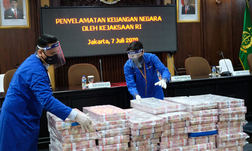 <p>Petugas merapikan barang bukti berupa uang sitaan di kantor Kejagung, Jakarta, Selasa, 7 Juli 2020. Kejagung mengeksekusi kilang LPG PT TLI di Tuban Jawa Timur dan uang senilai Rp 97 miliar hasil korupsi terpidana penjualan kondensat di BP Migas Honggo Wendratno. Foto: Ismail Pohan/TrenAsia</p>
