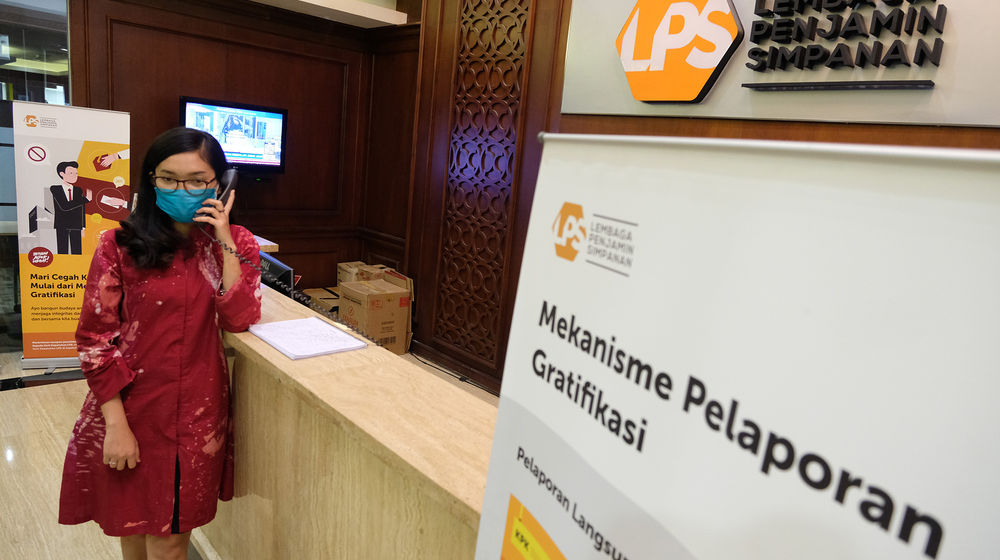 <p>Karyawan beraktivitas didekat logo Lembaga Penjamin Simpanan (LPS) di Jakarta, Jum’at, 10 Juli 2020.  Lembaga Penjamin Simpanan (LPS) diberikan kewenangan tambahan berupa penyelamatan bank sakit dan penempatan dana pada bank yang kesulitan likuiditas selama pandemi Covid-19. Penempatan dana oleh LPS tersebut bertujuan untuk mengelola dan/atau meningkatkan likuiditas LPS, serta mengantisipasi dan/atau melakukan penanganan stabilitas permasalahan sistem keuangan yang dapat menyebabkan kegagalan bank. Kewenangan tersebut diatur dalam Peraturan Pemerintah No.33/2020 yang mengatur mengenai Pelaksanaan Kewenangan LPS. Foto: Ismail Pohan/TrenAsia</p>
