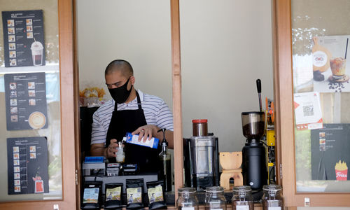 <p>Ahmad Hilmy Almusawa (22) penyandang tuna netra menyiapkan pesanan kopi untuk pelanggan di gerainya &#8220;Mata Hati Koffie&#8221;, kawasan Pondok Cabe, Tangerang Selatan, Kamis, 23 Juli 2020. Meski dalam situasi pandemi, Hilmy yang sudah mengalami kebutaan sejak umur 12 tahun ini tetap semangat meracik kopi dengan hati di gerai miliknya sendiri tersebut. Omset yang menurun tidak serta merta menurunkan semangatnya untuk tetap menjalankan bisnisnya dengan sepenuh hati melayani setiap penikmat kopi yang datang tak terkecuali pelanggan setianya. Foto: Ismail Pohan/TrenAsia</p>
