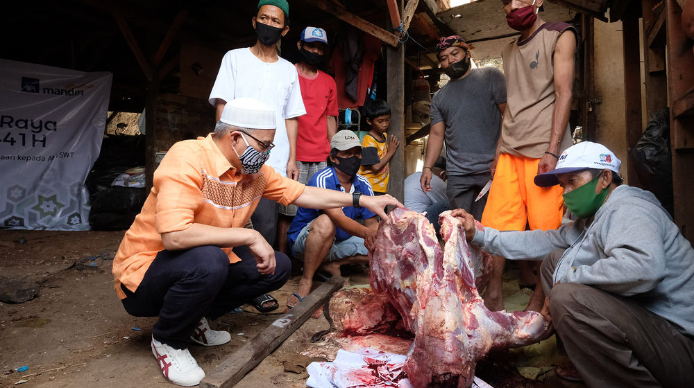 <p>Direktur Kepatuhan PT. AXA Mandiri Financial Services (AXA Mandiri) Rudy Kamdani (kiri) menyaksikan pembagian daging kurban di kampung Pemulung Pelangi, Cipete Utara, Jakarta Selatan, Jumat, 31 Juli 2020. Penyerahan hewan kurban ini ditujukan kepada masyarakat pengepul barang bekas di Kampung Pemulung Pelangi dalam memperingati Hari Raya Idul Adha 1441 Hijriah. Program ini merupakan salah satu rangkaian kegiatan AXA Mandiri sebagai bagian dari Mandiri Group dalam program Mandirian Cinta Indonesia sebagai wujud kepedulian perusahaan terhadap masyarakat terdampak pandemi Covid-19. Kegiatan di lebaran haji kali ini memiliki semangat untuk berbagi dalam menjalin kerukunan, mempererat tali persaudaraan, serta saling bertoleransi bersama masyarakat sekitar. Foto: Ismail Pohan/TrenAsia</p>
