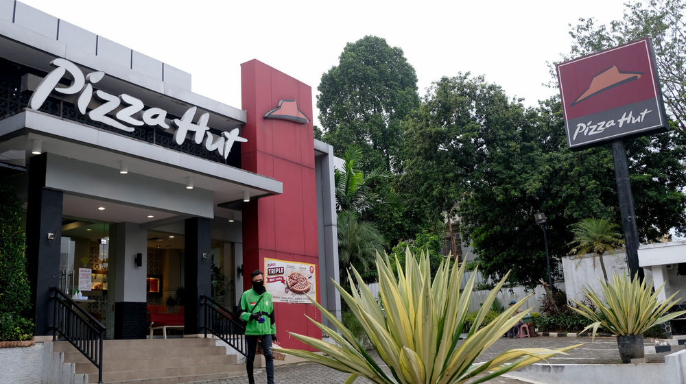 <p>Mitra ojek online melintas usai mengambil pesanan di Gerai Pizza Hut, Jakarta, Kamis 2 Juni 2020. Pemegang lisensi terbesar dari waralaba restoran Pizza Hut di Amerika Serikat, NPC International Inc., mengajukan bangkrut akibat penjualan yang anjlok drastis selama pandemi virus corona atau Covid-19. Namun demikian, PT Sarimelati Kencana, pengelola gerai Pizza Hut di Indonesia masih mengantongi laba Rp 6,04 miliar sepanjang kuartal I 2020. Jumlah ini turun 85% dibandingkan periode sama tahun 2019 yang mencapai Rp 40,18 miliar. Foto: Ismail Pohan/TrenAsia</p>
