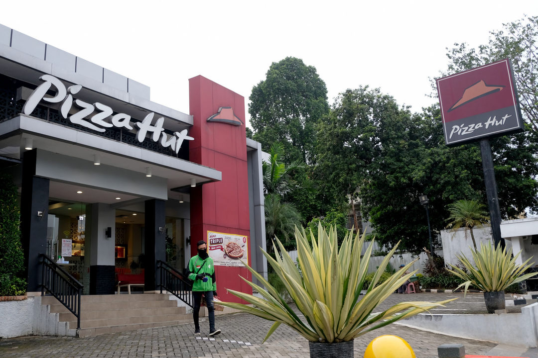 <p>Mitra ojek online melintas usai mengambil pesanan di Gerai Pizza Hut, Jakarta, Kamis 2 Juni 2020. Pemegang lisensi terbesar dari waralaba restoran Pizza Hut di Amerika Serikat, NPC International Inc., mengajukan bangkrut akibat penjualan yang anjlok drastis selama pandemi virus corona atau Covid-19. Namun demikian, PT Sarimelati Kencana, pengelola gerai Pizza Hut di Indonesia masih mengantongi laba Rp 6,04 miliar sepanjang kuartal I 2020. Jumlah ini turun 85% dibandingkan periode sama tahun 2019 yang mencapai Rp 40,18 miliar. Foto: Ismail Pohan/TrenAsia</p>
