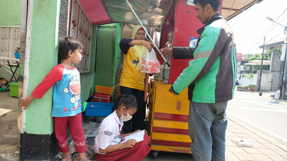<p>Keysha (8) mengikuti pelajaran secara online sementara ibundanya melayani pembeli di gerai ayam krispy tempat ibunya bekerja, di Jalan Bukit Duri Tanjakan, Gang Langgar, Jakarta Selatan, Selasa, 28 Juli 2020. Foto: Ismail Pohan/TrenAsia</p>
