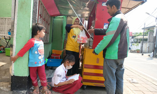 <p>Keysha (8) mengikuti pelajaran secara online sementara ibundanya melayani pembeli di gerai ayam krispy tempat ibunya bekerja, di Jalan Bukit Duri Tanjakan, Gang Langgar, Jakarta Selatan, Selasa, 28 Juli 2020. Foto: Ismail Pohan/TrenAsia</p>
