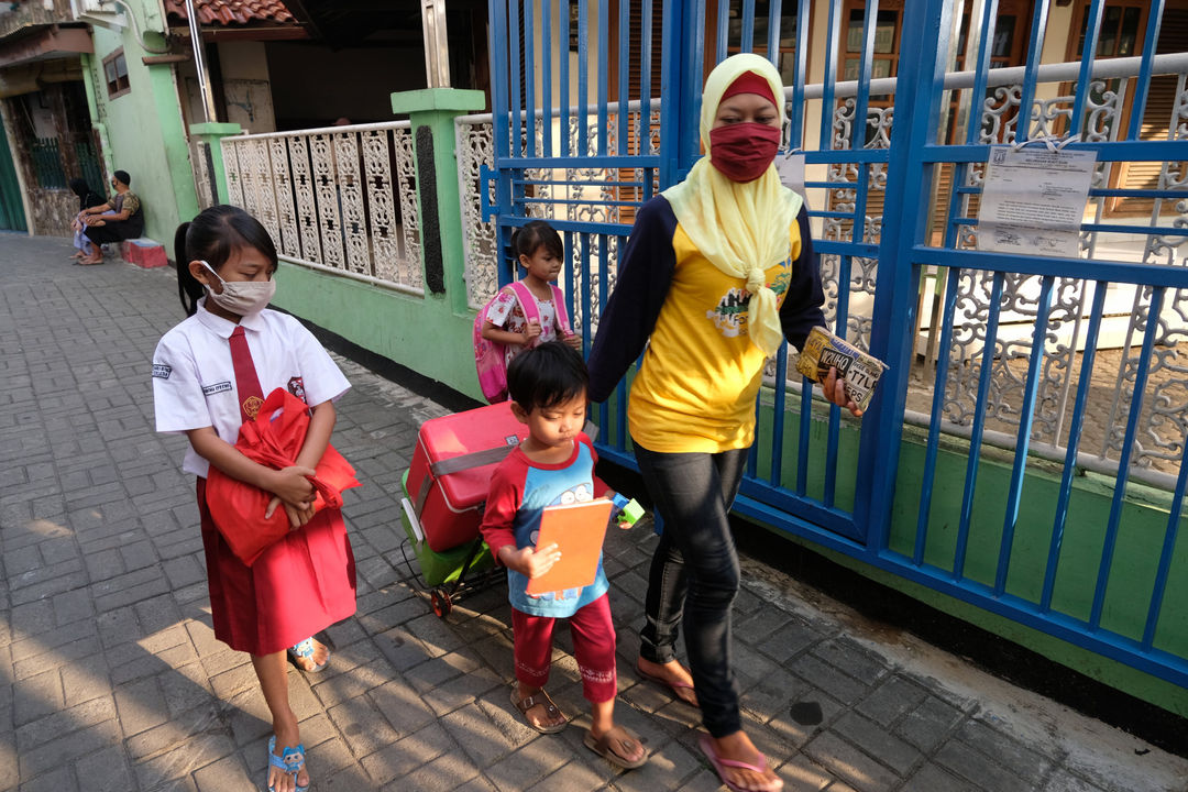 <p>Keysha (8) berjalan bersama ibunda dan adiknya untuk mengikuti pelajaran secara online di gerai ayam krispy tempat ibunya bekerja, di Jalan Bukit Duri Tanjakan, Gang Langgar, Jakarta Selatan, Selasa, 28 Juli 2020. Anak pertama dari tiga bersaudara pasangan Firman (32) dan Okta (31) tampak tekun mengikuti pelajaran berbasis online di masa kernormalan baru saat ini. Keluarga yang terdampak secara ekonomi akibat  ayahnya yang dirumahkan dari pekerjaan, membuat ibunya harus turun tangan dengan bekerja di gerai ayam krispy milik tetangga mereka. Belum lagi sistem sekolah online yang memaksa orang tua Keysha harus menyisihkan penghasilan untuk membeli pulsa Rp 25000 per minggu agar anak mereka dapat terus belajar. Ditengah himpitan ekonomi, Keysha yang bercita-cita menjadi seorang dokter ini terus memupuk semangatnya untuk belajar agar bisa membanggakan keluarga, sembari berdoa agar ayahnya kembali mendapatkan pekerjaan dan badai corona segera berakhir. Foto: Ismail Pohan/TrenAsia</p>
