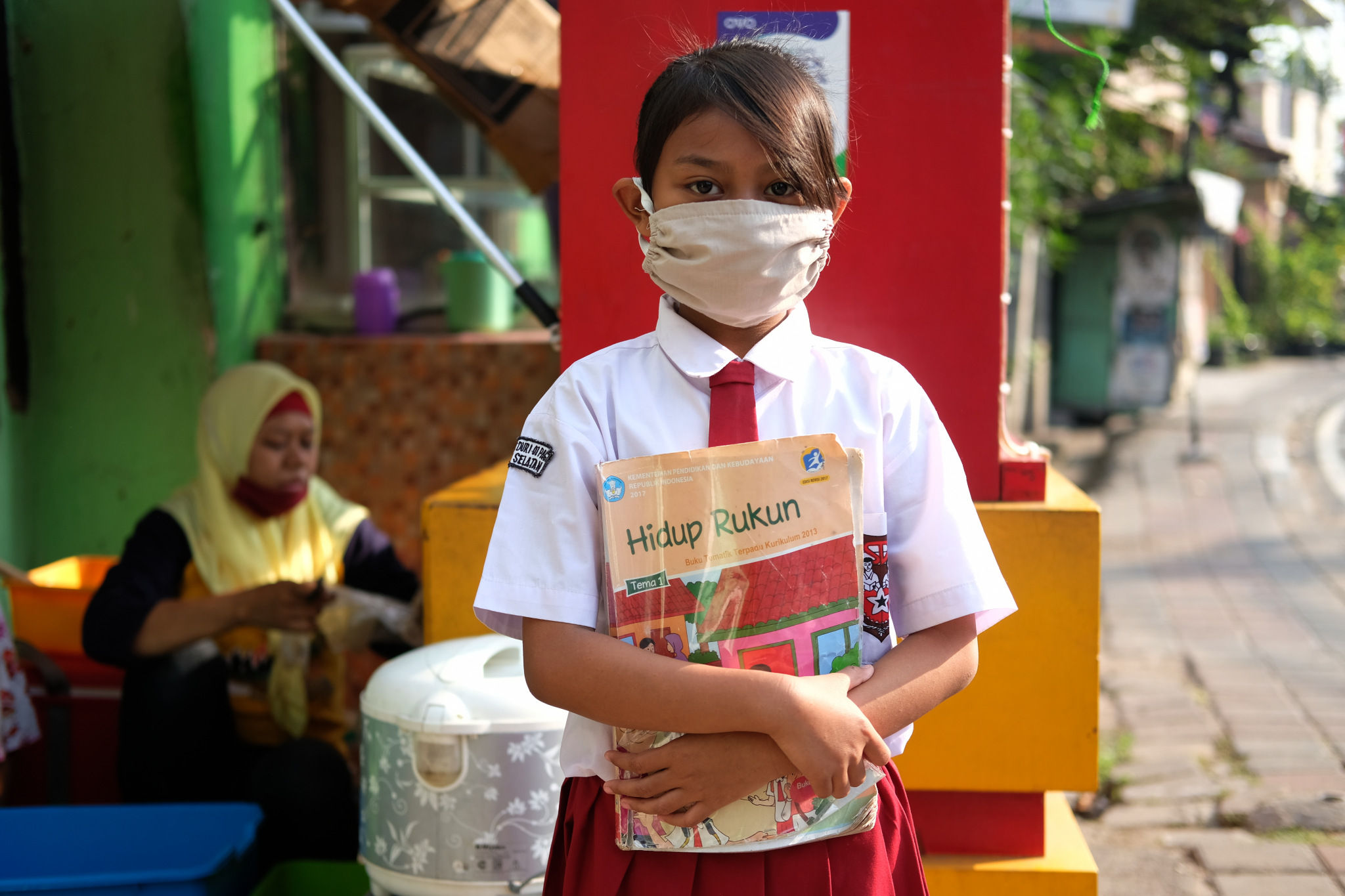 <p>Keysha (8) berpose sebelum mengikuti pelajaran secara online di gerai ayam krispy tempat ibunya bekerja, di Jalan Bukit Duri Tanjakan, Gang Langgar, Jakarta Selatan, Selasa, 28 Juli 2020. Anak pertama dari tiga bersaudara pasangan Firman (32) dan Okta (31) tampak tekun mengikuti pelajaran berbasis online di masa kernormalan baru saat ini. Keluarga yang terdampak secara ekonomi akibat  ayahnya yang dirumahkan dari pekerjaan, membuat ibunya harus turun tangan dengan bekerja di gerai ayam krispy milik tetangga mereka. Belum lagi sistem sekolah online yang memaksa orang tua Keysha harus menyisihkan penghasilan untuk membeli pulsa Rp 25000 per minggu agar anak mereka dapat terus belajar. Ditengah himpitan ekonomi, Keysha yang bercita-cita menjadi seorang dokter ini terus memupuk semangatnya untuk belajar agar bisa membanggakan keluarga, sembari berdoa agar ayahnya kembali mendapatkan pekerjaan dan badai corona segera berakhir. Foto: Ismail Pohan/TrenAsia</p>
